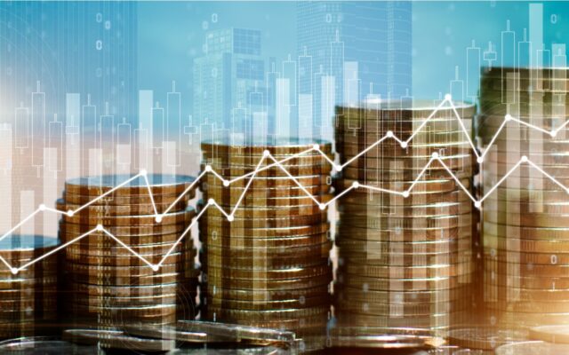 Image of coins stacked in various heights with a charts digitally overlaid to show performance of financial metrics against a sky blue background.