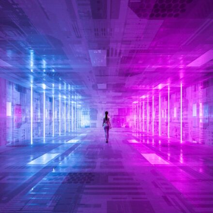 Digital image of a businesswoman walking along a futuristic corridor, lit in purple and blue.