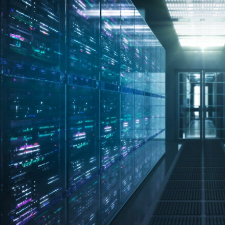 Row of servers inside closed section of data center, with view from hallway towards door in the background.