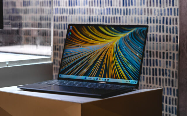 Dell Latitude 9440 laptop with image on the display on a stand in front of a brick wall.