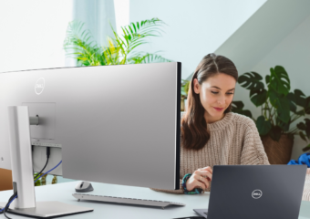 Woman working remotely using a Dell UltraSharp 49 Curved USB-C Hub Monitor and a Dell Latitude 5000 series model laptop.