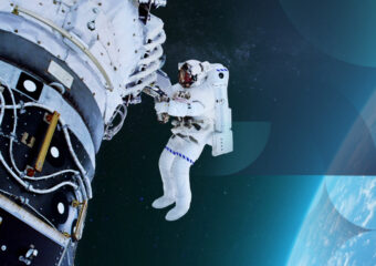 Astronaut in an EVA suit outside their spacecraft, working on mission payload project. Image has textured pattern subtly overlaid.