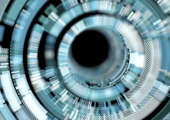 Digitally rendered image, close up of futuristic interface, with blue, white, silver, and gray colors around a black circular center.