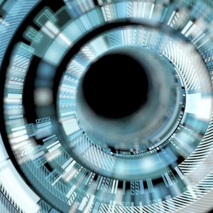 Digitally rendered image, close up of futuristic interface, with blue, white, silver, and gray colors around a black circular center.