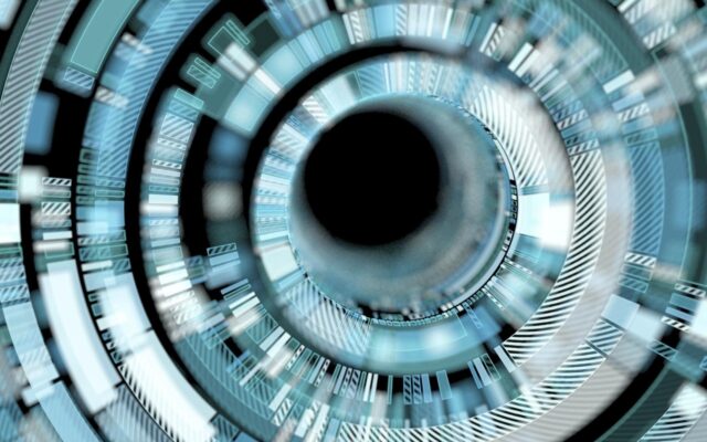 Digitally rendered image, close up of futuristic interface, with blue, white, silver, and gray colors around a black circular center.
