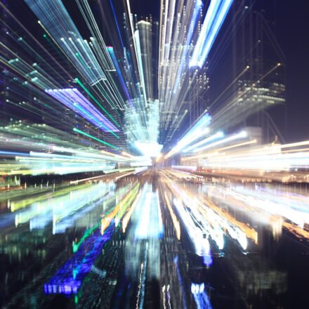 Unfocused image of a city's downtown area at night, with building and city lights radiating outward.