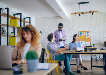 Businesswoman using laptop at modern office, her colleagues are working in the background
