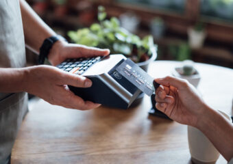 Close up of a woman's hand paying bill with credit card in a cafe, scanning on a card machine. Electronic payment. Banking and technology
