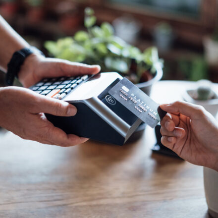 Close up of a woman's hand paying bill with credit card in a cafe, scanning on a card machine. Electronic payment. Banking and technology